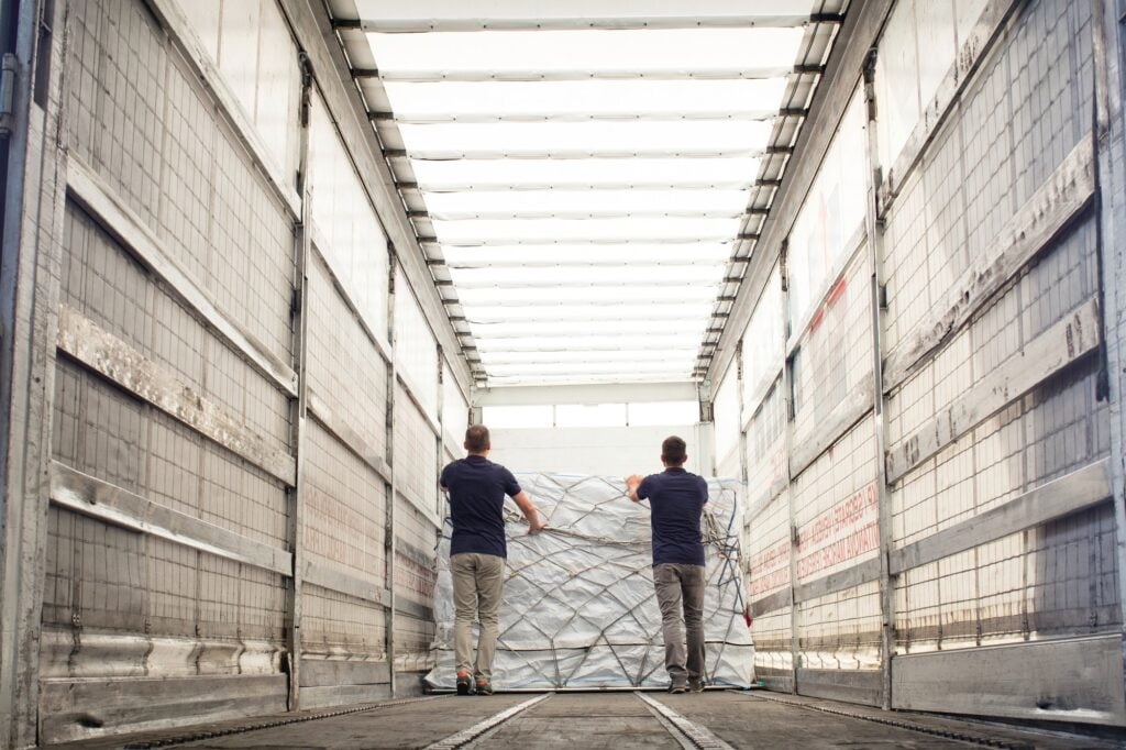 Workers pushing freight in air freight container